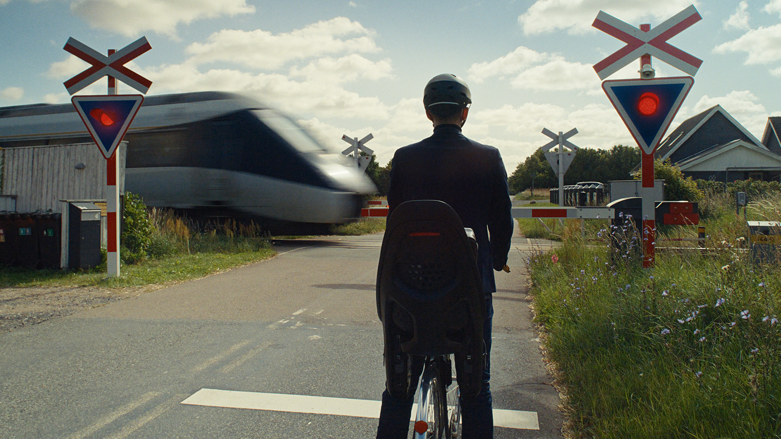Cyklist der holder stille foran overkørsel, hvor toget er ved at køre forbi